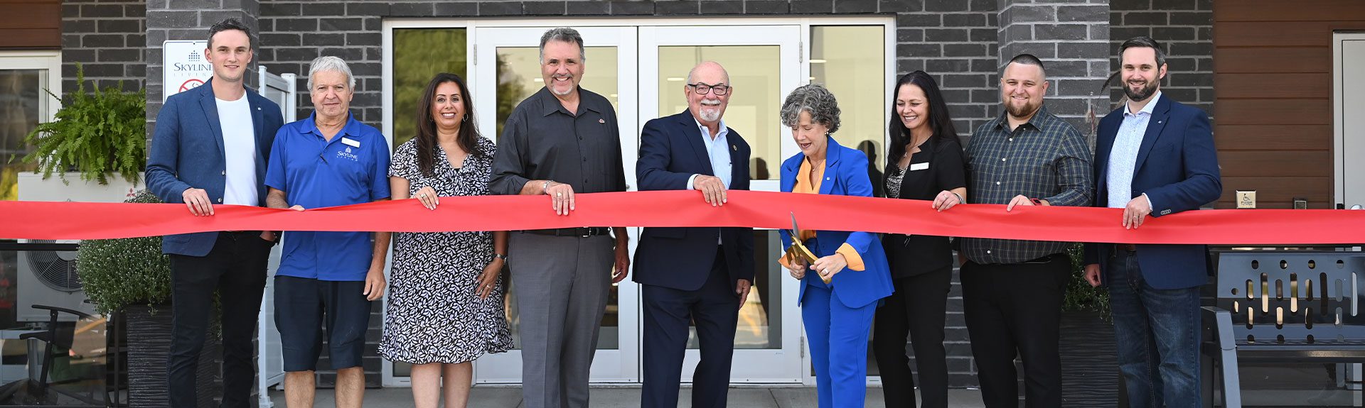 Skyline staff and dignitaries cut the ribbon on a new apartment building.